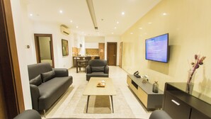 A modern living room with a sofa, armchair, coffee table, and TV. - Spacious Two Bedroom Luxury at Avant Garde (Accra)