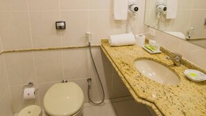 Un baño con inodoro, bidé, lavamanos y espejo.