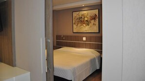 Ein Schlafzimmer mit zwei Betten, einem Holzkopfstück, einem Bild an der Wand und einer Deckenleuchte.