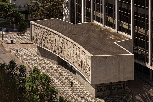 A modern building with a curved facade featuring intricate bas-relief artwork.