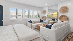 A modern, well-lit room with a large bed, two white sofas, a coffee table, and a large mirror. - New to 30A! Freshly Renovated, Walk to Seaside, Pool, Easy Beach Access (Santa Rosa Beach)
