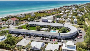 A coastal hotel with a curved building, a swimming pool, and a parking lot. - New to 30A! Freshly Renovated, Walk to Seaside, Pool, Easy Beach Access (Santa Rosa Beach)