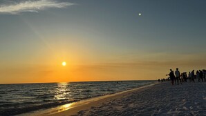 A beach scene with the sun setting over the ocean, people walking along the shore. - New to 30A! Freshly Renovated, Walk to Seaside, Pool, Easy Beach Access (Santa Rosa Beach)