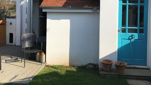 A house with a red roof, a blue door, and a small patio area with a chair and pots. - End terrace, sea views,short walk to the town and harbour of Ilfracombe (Ilfracombe)