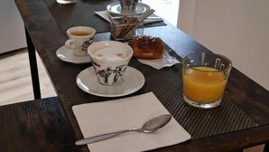 A breakfast setup with a table, a glass of orange juice, a cup of coffee, a pastry, and a spoon on a napkin. - Le Chiavi di Polido (Aversa)