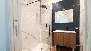 A modern bathroom with a glass shower enclosure, a wooden vanity, and a dark tiled wall. - Le Chiavi di Polido (Aversa)