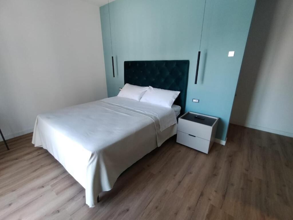 A bedroom with a bed, a nightstand, and a wardrobe.