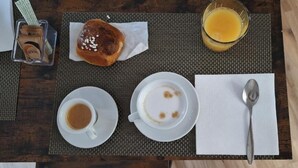 A breakfast setting with a croissant, two cups of coffee, a glass of orange juice, and a spoon on a wooden table. - Le Chiavi di Polido (Aversa)