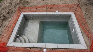 En fyrkantig pool med en kakelbeklädd kant och ett nät som fungerar som säkerhetsbarriär.