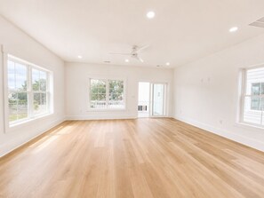 A spacious room with hardwood floors, large windows, and a ceiling fan. - 5 Bedroom, Private Pool, Elevator - Life's A Beach (Surfside Beach)