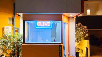 A building with a neon sign reading "OLIVE" and a small entrance with a door.