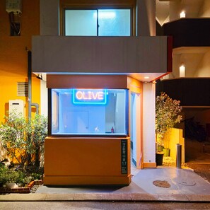 A building with a neon sign reading "OLIVE" and a small entrance with a door. - OLIVE stay (Fukuoka)