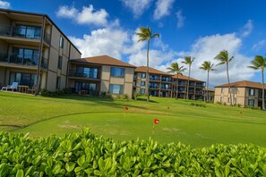 A golf course with a clubhouse and multiple-story buildings with balconies. - Pono Kai Resort Unit #G308 (Kapaa)
