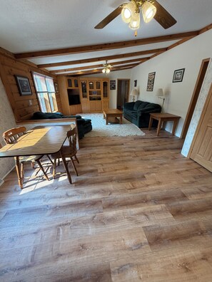 Un interior de madera con una mesa de comedor, sillas, un sofá y un ventilador de techo.
