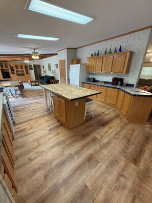Een keuken met houten kastjes, een centraal eiland en een eethoek met een tafel en stoelen.