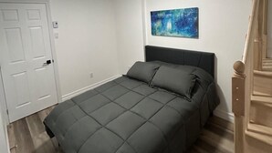 Un dormitorio con una cama, un cuadro en la pared y una escalera de madera.