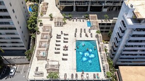 Vista aérea de una zona de piscina en la azotea, con múltiples sillones de descanso y una gran piscina.