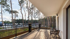 Un terrazzo in legno con ringhiera, una sedia e un tavolo.