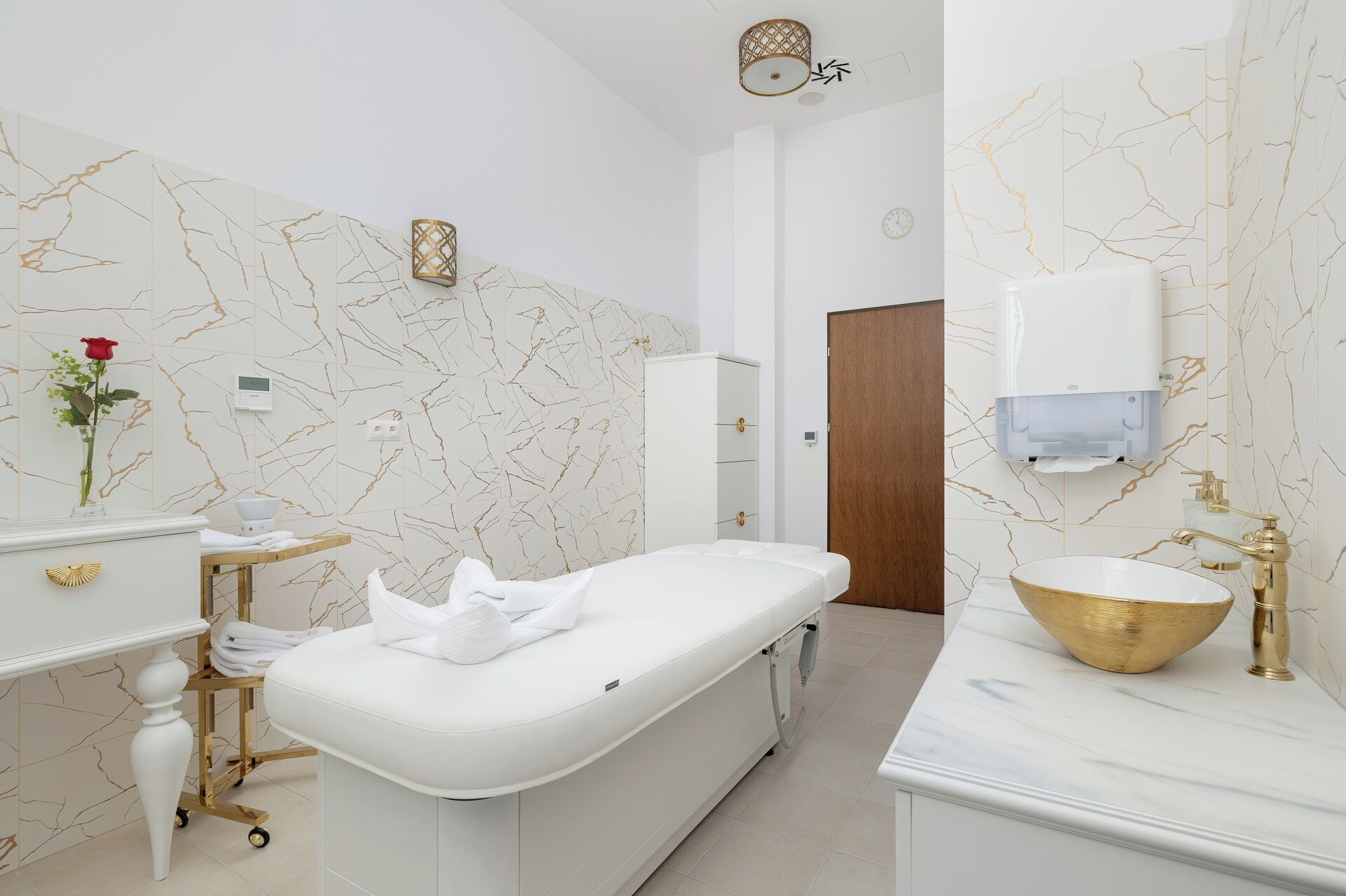Ein modernes Badezimmer mit einer freistehenden Badewanne, einem Waschtisch mit goldfarbenem Becken und Wänden mit Marmoroptik.