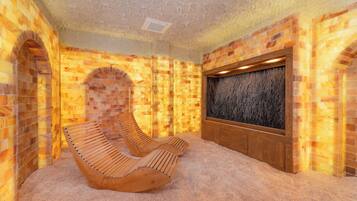 Un sauna con bancos de madera, pared de piedra y panel de madera con diseño texturizado.