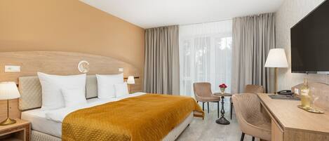 A hotel room with a bed, a desk, a chair, and a television.