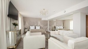 Una camera d'albergo moderna con un letto grande, un divano, una televisione e uno specchio di grandi dimensioni.