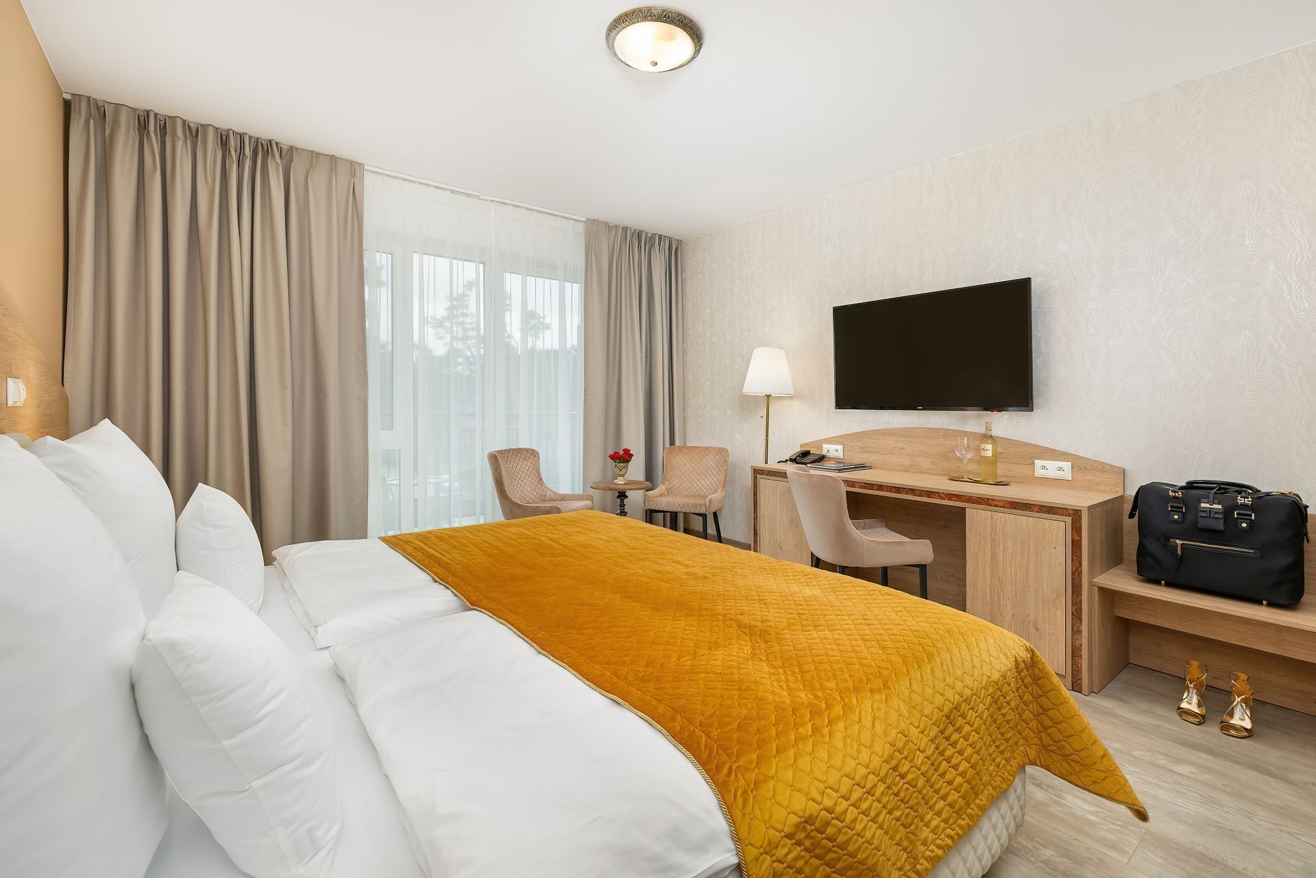 A hotel room with a bed, a desk, a chair, a TV, and a luggage rack.