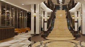 Un'ampia hall con una scalinata centrale, arredi moderni e un'area reception.