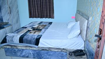 A bed with a patterned bedspread, a telephone on the side, and a patterned wall.