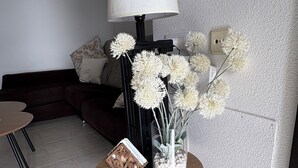 Ein Wohnzimmer mit einer Lampe, einer Vase mit Blumen und einem kleinen Tisch mit einem dekorativen Gegenstand.