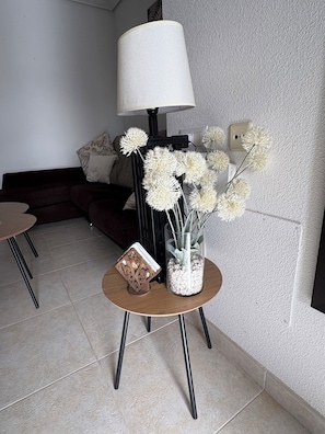 A living room with a lamp, a vase with flowers, and a small table with a decorative item. - Apartment on Avenue de la Mancha, across from the pool and a 15-minute walk to the beach (Torrevieja)