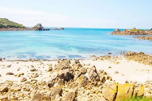 A rocky beach with clear blue water and distant rocky formations. - Charming house in the heart of the village (Plougasnou)