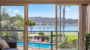 A balcony with a pool, a view of a lake, and a distant hill. - Fishpen Views - Merimbula (Merimbula)
