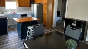 Une cuisine moderne avec des meubles en bois, un îlot central et un coin repas comprenant une table et des chaises.