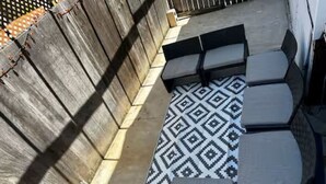 Une terrasse agrémentée d’un tapis à motifs, de meubles d’extérieur et d’une clôture en bois.