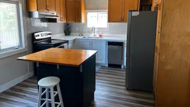 Une cuisine avec des meubles de rangement en bois, un plan de travail noir, une cuisinière blanche et un réfrigérateur.