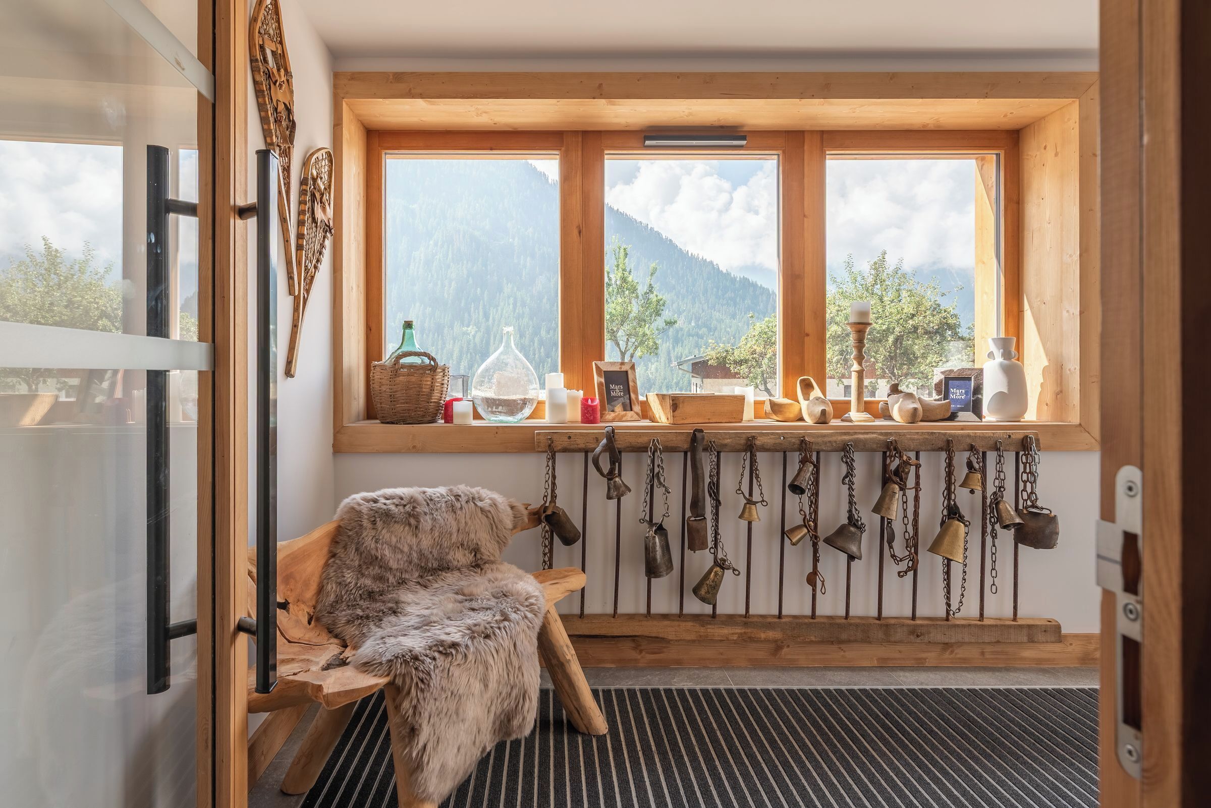 Un chalet rustique avec un banc en bois, une décoration murale de style rustique et une fenêtre donnant sur les montagnes.