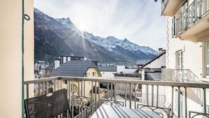 A balcony with a view of snow-capped mountains, a table, and a chair. - Brina – Chamonix Apartment with Mont Blanc View (Chamonix-Mont-Blanc)