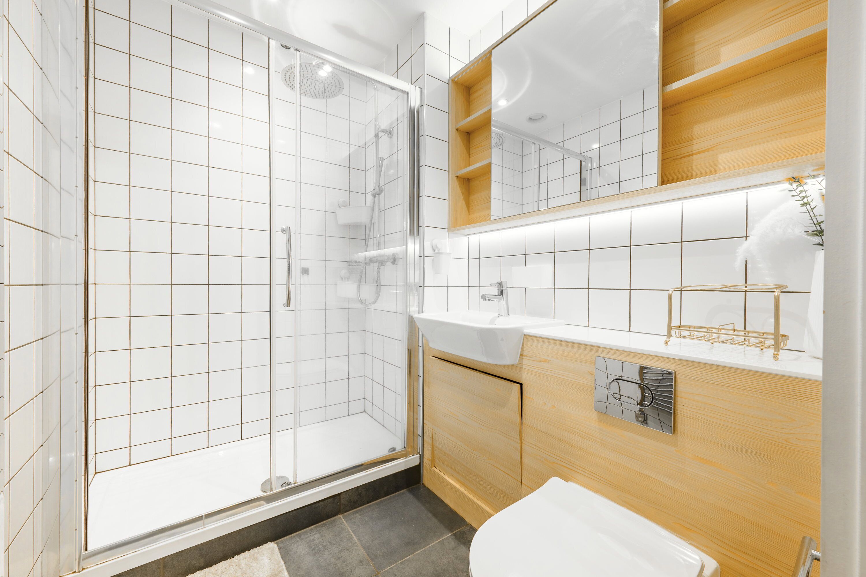 Une salle de bain moderne avec une douche à parois de verre, un lavabo blanc et des meubles en bois.