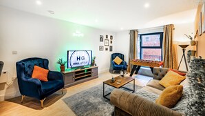A modern living room with a TV, sofas, a coffee table, and a foosball table. - Huge Digbeth Apt, Sleeps 8, 5bed, Free Parking. (Birmingham)