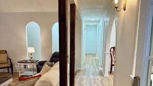 A spacious hallway with wooden flooring, a sofa, a table with a lamp, and a door with a keypad lock. - The Star Point Lakehouse · 3BR/2BA Retreat in Brandon (Brandon)