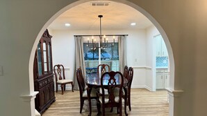 A dining area with a wooden table and chairs, a chandelier, and a view of a balcony. - The Star Point Lakehouse · 3BR/2BA Retreat in Brandon (Brandon)