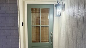A green door with a glass panel, a doormat with "welcome" written on it, and a textured wall to the right. - The Star Point Lakehouse · 3BR/2BA Retreat in Brandon (Brandon)