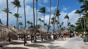Une plage avec des parasols en chaume et des palmiers.