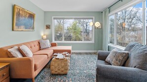 Un salon confortable avec une grande fenêtre, un canapé, une table basse et un tapis.