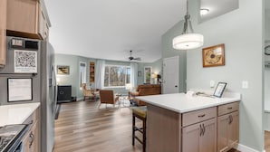 Une cuisine moderne avec des meubles en bois, un plan de travail blanc et un îlot central intégré.