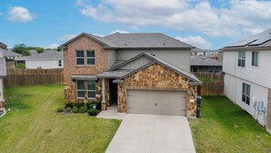 A two-story house with a stone facade, a garage, and a well-maintained lawn. - Spacious 4-bedroom house in charming Jarrell with AC (Jarrell)