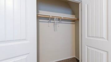 Un armario con barra de madera y ropa colgada.