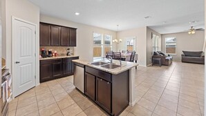 A spacious kitchen with dark cabinetry, a central island, and a dining area with a table and chairs. - Spacious 4-bedroom house in charming Jarrell with AC (Jarrell)