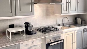 A modern kitchen with a gas stove, oven, built-in washing machine, and a coffee maker. - Elegant apartment for 6 people. Private elevator and large terrace. Milan. (Milano)